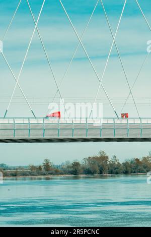 Roter Sattelzug, der die Brücke über die Donau in Novi Sad am sonnigen Frühlingstag überquert Stockfoto