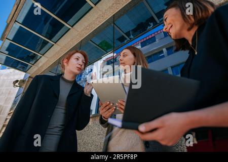 Low-Angle-View-Aufnahme einer schönen rothaarigen Geschäftsfrau, die ihren Kollegen etwas Lustiges erzählt Stockfoto