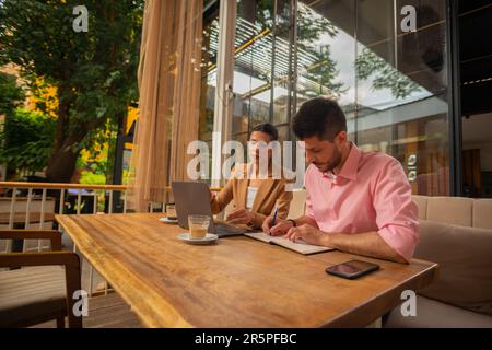 Zwei Geschäftspartner sitzen in einer Café-Bar und schreiben neue Ideen zu ihrem neuen Projekt Stockfoto