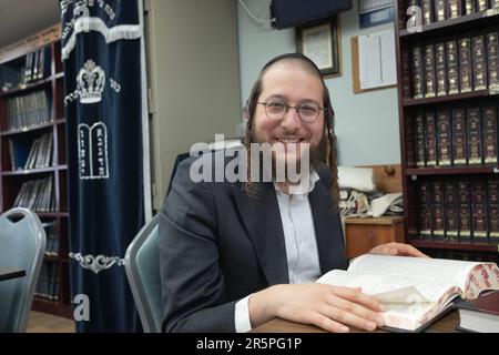 Ein orthodoxer Jude hält von seinem Talmud-Studium an, um für dieses Foto zu lächeln. In Monsey, Rockland County, New York. Stockfoto