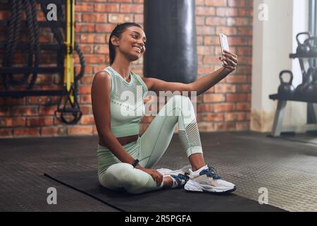Fitnessstudio, Fitness oder glückliche Frau, die Selfie beim Workout, Training oder Trainingspause für soziale Medien macht. Wellness, Lächeln oder gesundes, lächelndes indisches Mädchen Stockfoto