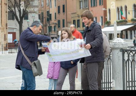 Eine Gruppe italienischer Touristen halten eine Italienische Karte von Venedig und die umliegenden Inseln in Campo Giovanni & Paolo in Venedig. Stockfoto