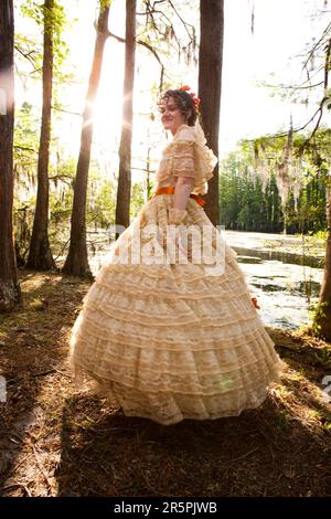 Eine junge Frau posiert in einem Southern Belle Outfit, einschließlich eines großen, kunstvoll verzierten Kostüms, in der Nähe eines Sees. Stockfoto
