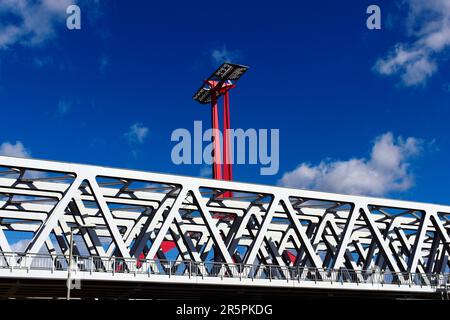 Nahaufnahme der Stahlbahnbrücke aus perspektivischer Sicht. Roter Stahlturm mit Sonnenkollektoren. Blauer Himmel mit weißen Wolken. Stabbalken mit dreieckigen Elementen Stockfoto