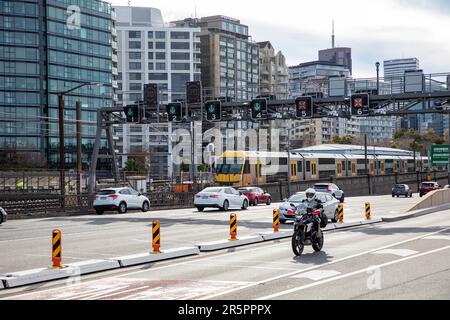 Motorradfahrer und Sydney-Zug am Milsons Point nähern sich der Hafenbrücke, Sydney, NSW, Australien Stockfoto