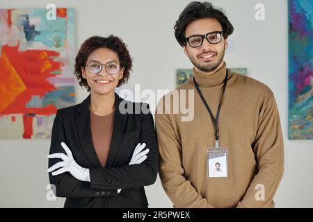 Porträt eines jungen Mitarbeiterpaares, das während der Arbeit in einer Kunstgalerie vor der Kamera lächelt Stockfoto