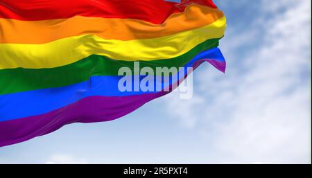Die Regenbogenflagge winkt an klaren Tagen. Bunte Flagge mit Streifen in den Farben des Regenbogens, oft als Symbol des LGBT-Stolzes verwendet. 3D Abbildung Stockfoto