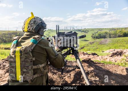 Ein Soldat der ukrainischen Streitkräfte feuert während der Schussübung eine automatische Waffe ab. Erschießungstraining des 128. Territorialen Verteidigungsbataillons der ukrainischen Streitkräfte in der Region Donezk. Stockfoto