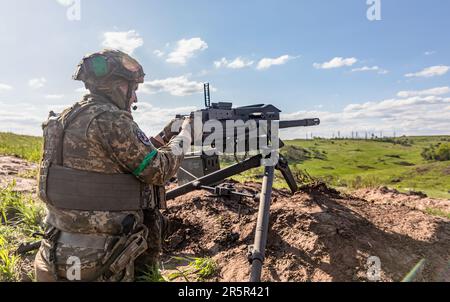 Ein Soldat der ukrainischen Streitkräfte feuert während der Schussübung eine automatische Waffe ab. Erschießungstraining des 128. Territorialen Verteidigungsbataillons der ukrainischen Streitkräfte in der Region Donezk. Stockfoto