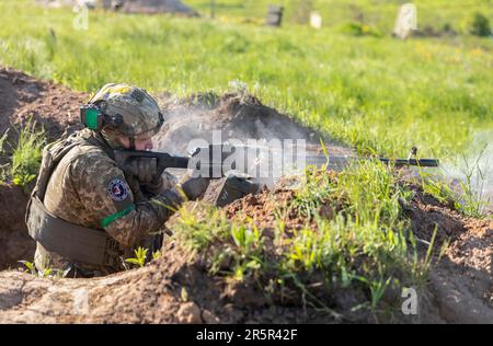 Ein Soldat der ukrainischen Streitkräfte feuert während der Schussübung eine automatische Waffe ab. Erschießungstraining des 128. Territorialen Verteidigungsbataillons der ukrainischen Streitkräfte in der Region Donezk. Stockfoto
