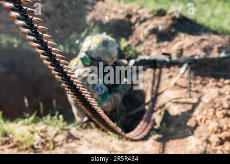 Ein Soldat der ukrainischen Streitkräfte feuert während der Schussübung eine automatische Waffe ab. Erschießungstraining des 128. Territorialen Verteidigungsbataillons der ukrainischen Streitkräfte in der Region Donezk. Stockfoto