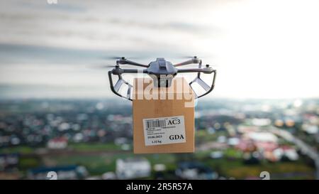 Die Drohne fliegt mit einem Paket für den Kunden über die Stadt – eine Nahaufnahme des Geräts, das Konzept der Drohnenlieferung. Stockfoto