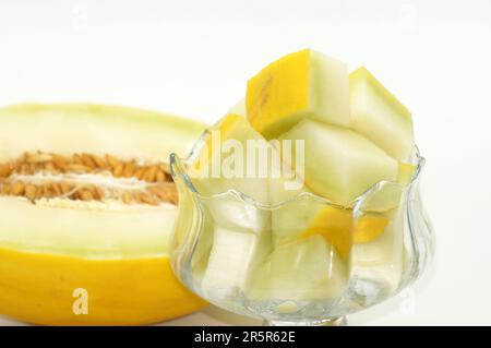 Eine farbenfrohe Auswahl an lebendigen Früchten wird in einer klaren Glasschüssel auf einem Holztisch in einer natürlichen Umgebung präsentiert Stockfoto