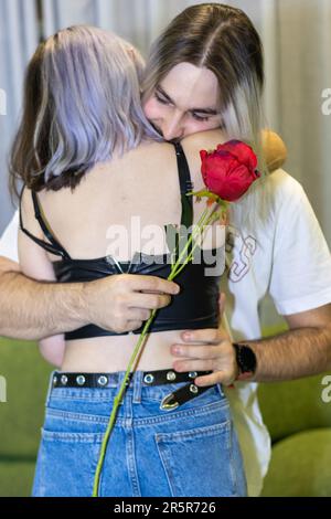 Ein glückliches Paar, das sich umarmt, während es vor seiner Wohnzimmercouch steht Stockfoto