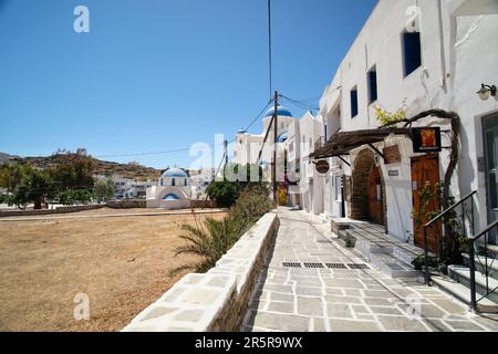 IOS, Griechenland - 21. Mai 2021 : Blick auf eine typische Gasse mit Bars, Geschäften und der Kathedrale auf der malerischen Insel iOS Greece Stockfoto