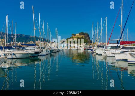 Denia, Alicante, Spanien. 22. Mai 2022 - Segelboote und andere Boote liegen im Yachthafen vor. Im Hintergrund: Hotels und Restaurants in der Altstadt, und Stockfoto