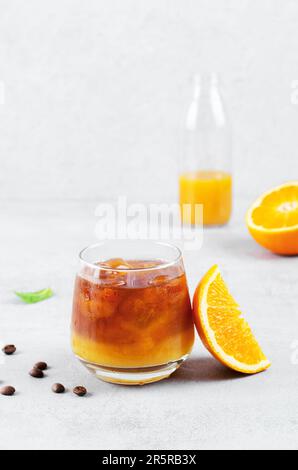 Bumble Coffee, Kaffee mit Orangensaft mit Eis, erfrischendes Getränk auf hellgrauem Hintergrund Stockfoto