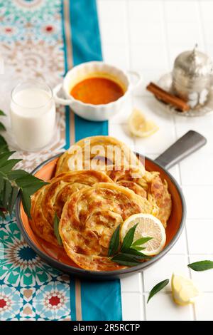 Roti Parata oder Roti Canai mit Lamm-Curry-Sauce, Joghurt und Zimttee Stockfoto