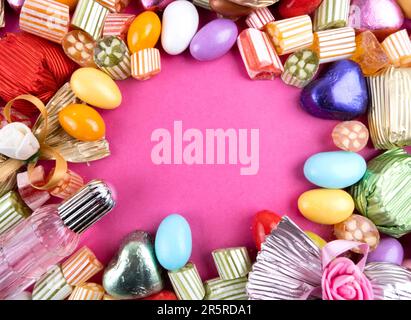 Sugar Feast Social Media Post Hintergrund mit Kopierraum. Rosafarbener Hintergrund. Bunte Süßigkeiten, eingepackte Luxusschokolade. Mandelbonbons. Zucker. Stockfoto