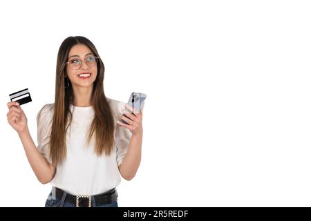 Online-Shopping oder -Banking, begeisterte kaukasische Brünette mit Smartphone- und kreditkarteneinkauf oder Online-Banking. Stehender weißer Hintergrund. Stockfoto