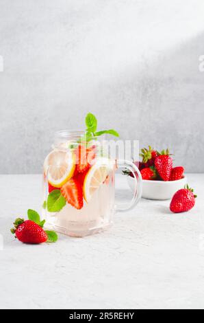 Erdbeerwasser, erfrischender Cocktail, Limonade, Detox, Sommereis mit frischen Erdbeeren, Zitrone und Minze auf hellem Hintergrund Stockfoto