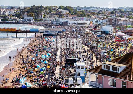 Tausende von Touristen und Urlaubern beobachten, wie die Roten Pfeile auf der englischen Riviera 2023 Airshow über Paignton in den Himmel steigen Stockfoto