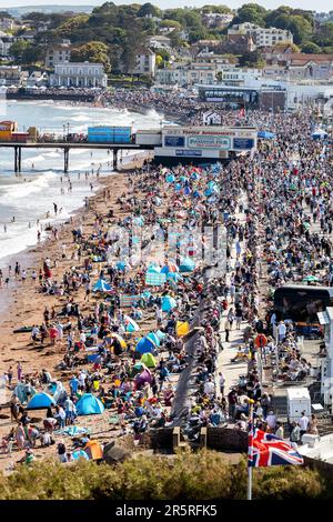 Tausende von Touristen und Urlaubern beobachten, wie die Roten Pfeile auf der englischen Riviera 2023 Airshow über Paignton in den Himmel steigen Stockfoto