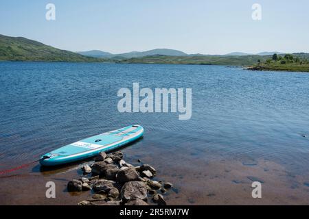 Stand Up Paddleboard auf Loch, Highlands Stockfoto