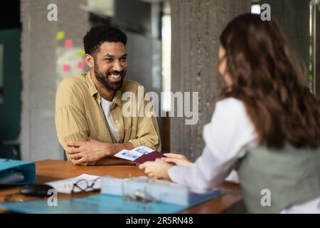 Nahaufnahme eines jungen, gutaussehenden Mannes im Reisebüro, der Flugtickets kauft. Stockfoto