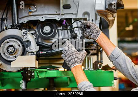 Arbeiter installiert Kunststoffkiste auf der Fahrzeugseite in der Werkstatt Stockfoto