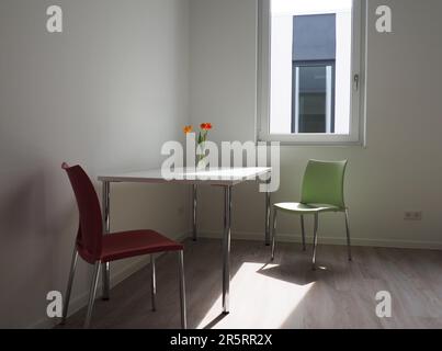 Ein heller, sonniger Speisesaal mit warmem Licht, das durch ein offenes Fenster strömt. Stockfoto