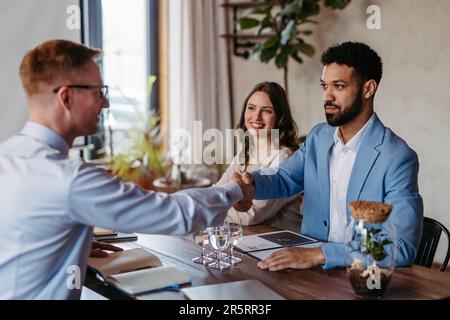 Lächelnde Geschäftspartner, die sich nach Erfolg die Hand schütteln. Stockfoto