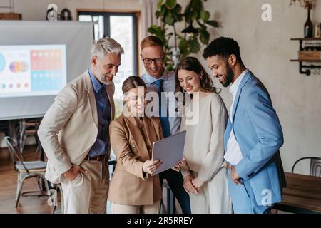 Porträt eines erfolgreichen kreativen Business-Teams, das zusammensteht und ein Tablet sucht. Stockfoto