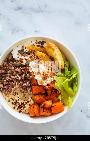 Vegetarische buddha-Schüssel mit Buchweizen, Hüttenkäse, Hummus und gebackener Süßkartoffel, Blick von oben. Ausgewogenes Speisekonzept. Stockfoto