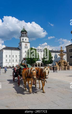 Salzburg, Österreich - 06.01.2023: Traditionelle Sightseeing-Pferdekutsche mit Touristen am Residenzplatz von Salzburg. Stockfoto