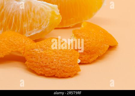 Ganze orangefarbene und orangefarbene Scheiben mit orangefarbener Schale auf orangefarbenem Hintergrund. Motivfoto. Hochwertiges Foto. Horizontal Stockfoto