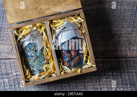 Glasbecher mit Blumentee und Glasbecher mit Kiefernkonfitüre in einer hölzernen Geschenkbox auf einem Tisch, Nahaufnahme. Schönes Geschenk für Familie und Freunde Stockfoto