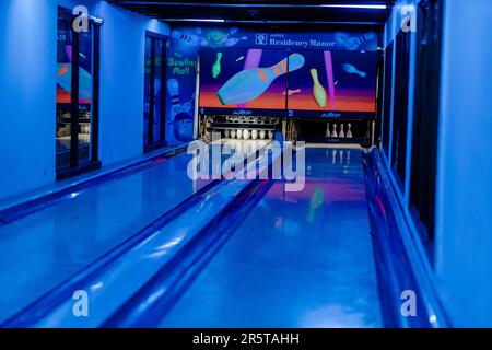 Eine Gruppe von Leuten spielt ein virtuelles Bowling-Spiel auf einem großen Flachbildschirm Stockfoto