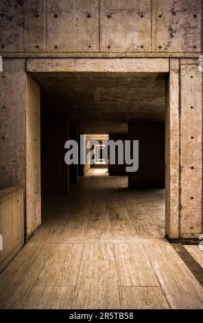 Innenansicht eines unterirdischen Gebäudes mit einer Tür an Zementwänden und einem Holzboden Stockfoto