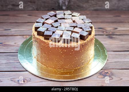 Schokoladen-Brownie-Kuchen mit Schokoriegeln und Trüffeln im rustikalen Hintergrund. Kuchen für Schokoladenliebhaber Stockfoto