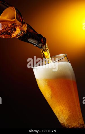 Bier aus einer Flasche in ein großes Glas gießen. Stockfoto