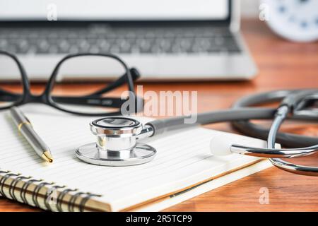 Ein moderner Schreibtisch mit einem Laptop, einer Brille und einem medizinischen Stethoskop auf dem Arbeitsplatz Stockfoto