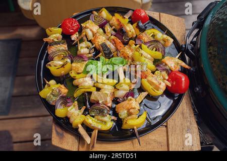 Fertig zum Essen - gegrillte Garnelen mit Lachs und Gemüse auf einem schwarzen Teller, von einem grill an einem Sommertag auf dem Balkon Stockfoto