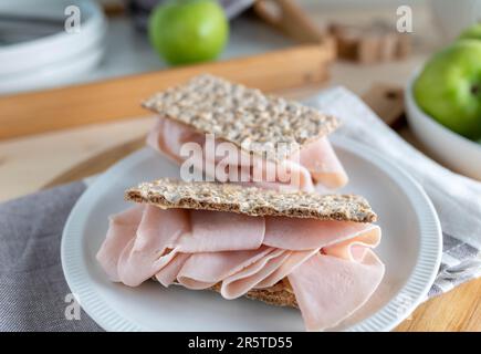 Kohlenhydratarmes Knäckebrot mit Hähnchenschinken zum Frühstück auf einem Teller Stockfoto