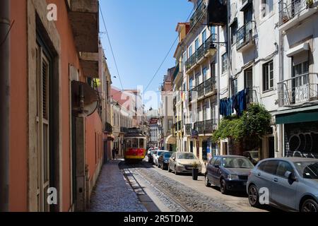 Straßenbahn Nr. 28E, die durch die engen Gassen von Lissabon fährt Stockfoto