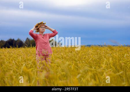 Ukrainische Frau mit einem Kranz auf dem Kopf in einem Weizenfeld, Symbol der ukrainischen Flagge Stockfoto