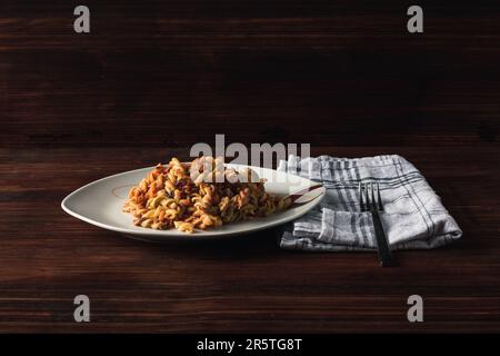 Ein Teller mit Thunfischsalat und Nudeln auf einem Holztisch Stockfoto