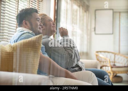 Junge asiatische mollige Paar Fernsehen-Serie und Film auf der Couch im Wohnzimmer. Mann und Frau genießen eine lustige Zeit zusammen zu Hause. Die Menschen lachen und lächeln zusammen Stockfoto