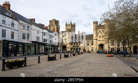 Die Türme der Kathedrale von Wells und das Pförtnerhaus des Bischofspalastes erheben sich hinter dem Marktplatz in der kleinen Stadt Somerset. Stockfoto