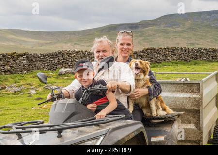 27.05.2023 Garsdale Head, Cumbria, Großbritannien. Bergbauer auf einem Quadbike mit seiner Familie und seinem Schäferhund Stockfoto